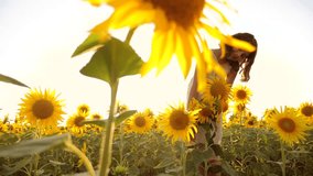 Happy little girl on the field of sunflowers sunlight in summer. beautiful sunset lifestyle little girl in sunflowers. slow motion video. girl teenager and sunflowers field concept agriculture