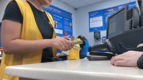 Port Coquitlam, BC, Canada - August 02, 2018 : Motion of worker counting money at customer service counter inside Walmart store with 4k resolution