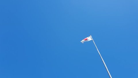 Japan Flag in the wind. Japan flag waving in slow motion against clean blue sky