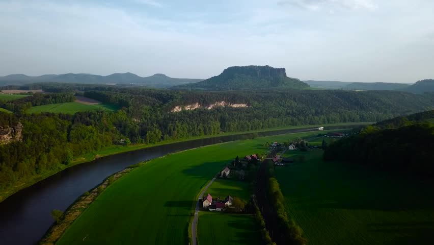 Aerial landscape shot over Elba river and some houses. A sandstone table mountain in the background.