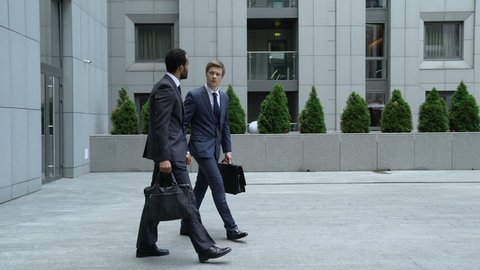 Businessmen talking outdoors, new employee trying to make friends with coworker