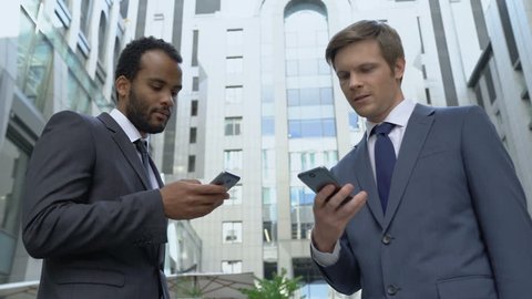 Two businessmen using smartphones, exchanging contacts, profitable acquaintance
