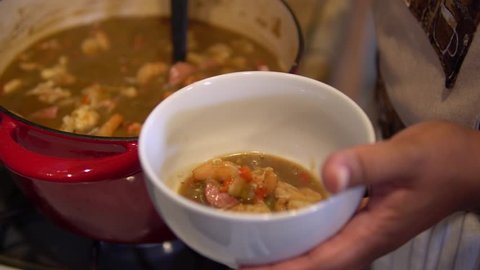 Cook serves up a bowl of shrimp and sausage gumbo with a ladle