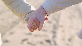 Cropped view of Lovely Elderly couple walking together on beach and holding each other hands