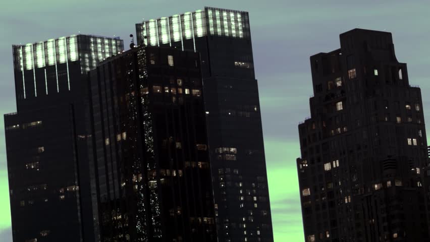 An abstract timelapse of a pair of modern office buildings silohuette at dusk in NYC.