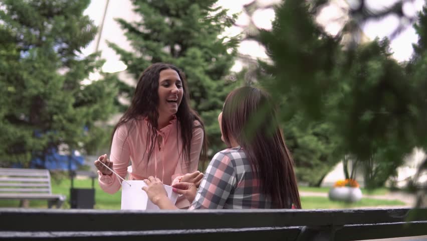 The girl after shopping runs up to her friend and shows her purchases in the package. slow motion.