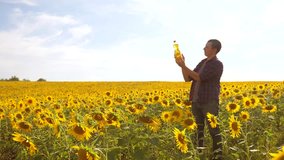 Man farmer hand hold bottle of sunflower oil the field at sunset. slow motion video. man farmer agriculture plastic bottle oil sunflower concept. man shows on the production of sunflower oil in a