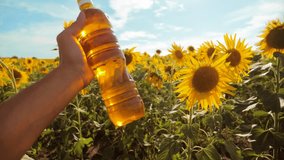 man farmer exploring the field with sunflowers. farmer holding a plastic bottle of sunflower oil in his hand field sunlight. slow motion video. blue sky background agriculture concept lifestyle