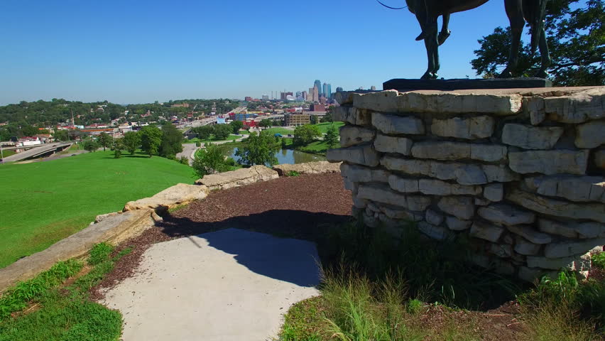 Slow rise reveals Kansas City and scout statue with a beautiful blue sky in Penn Valley Park.