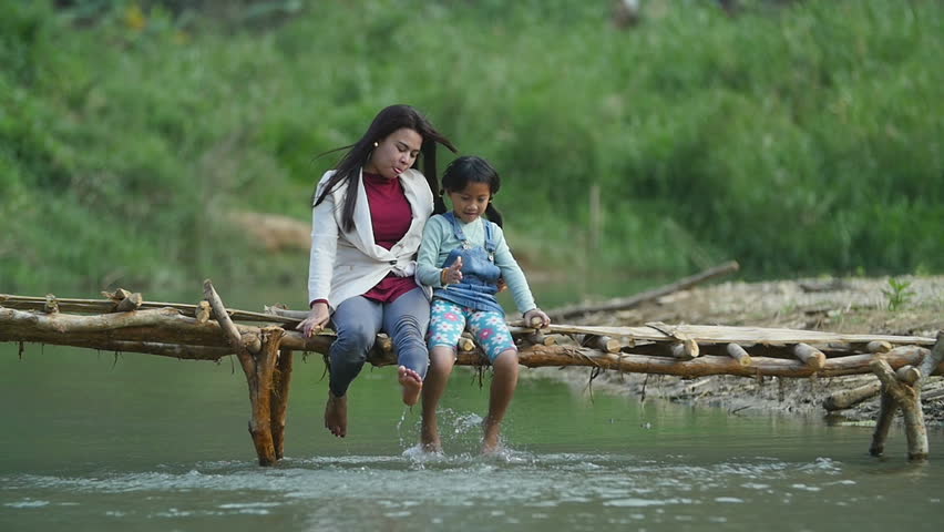 Asian Mother And Her Daughter Happy On A Bridge Crossing The River

