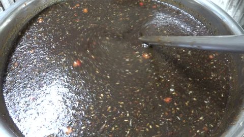 Stirring secret homemade Asian dark thick herbal spices seasoning sauce in a pot