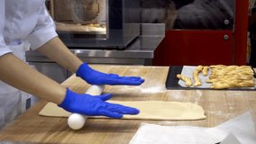 Preparation of the test for baking. Hands of the cook of the woman roll the dough with a rolling pin on the table. HD video
