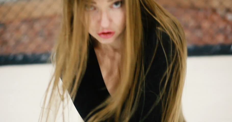 Young beautiful and fit woman with long hair dance go go very sensual and energetic in black dancer in mma cage arena octagon ring for fights.