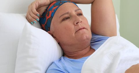 Painful cancer patient laying on bed in hospital room