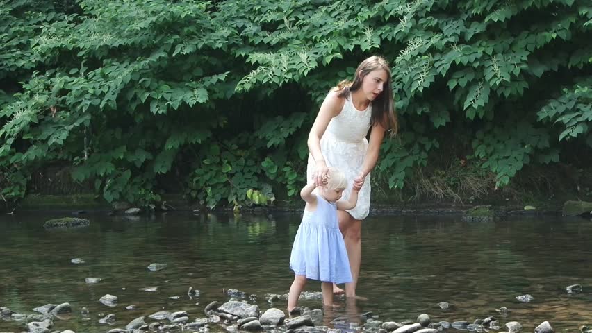 Mother with a little daughter are walking along the river