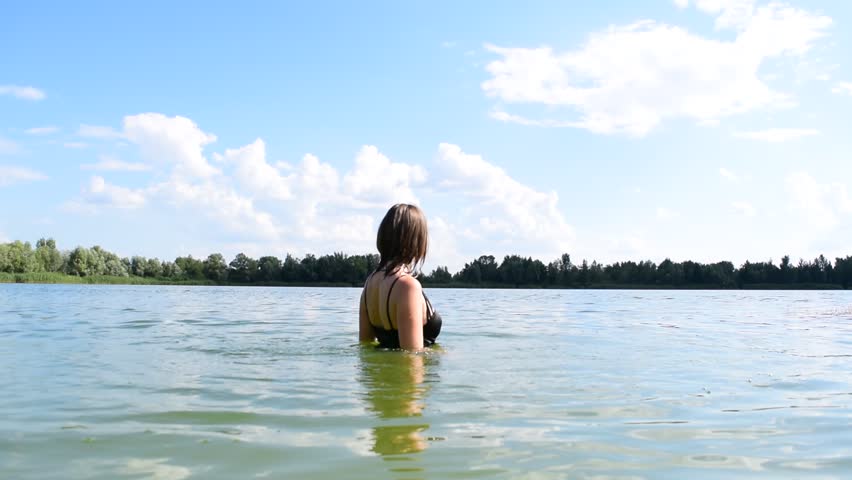 Young wet girl in the lake near the forest
