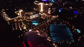 Aerial view on luxury resort hotel territory at night. Video. Night view of illuminated inner territory of hotel complex with footpaths, palms and pool. Tropical resort hotels at night top view.