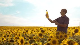 man farmer exploring the field with sunflowers. slow motion video. lifestyle Man farmer hand lifestyle hold bottle of sunflower oil the field at sunset. man farmer agriculture plastic bottle oil
