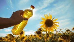 farmer holding a plastic bottle of sunflower oil in his hand field sunlight. slow motion video. blue sky background agriculture lifestyle concept sunflower oil bottle farming sunset field. man farmer