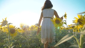 Happy little girl runs happy free across the field with sunflowers. slow motion video. smelling big sunflower on summer field. Delight of a pleasant smell. Summer holiday. concept lifestyle happiness