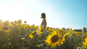 Happy little girl running happy free across the field with sunflowers. slow motion video . smelling big sunflower on summer field. Delight of a pleasant smell. Summer holiday. concept lifestyle