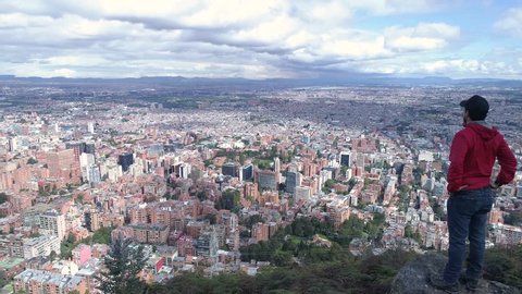 Aerial view of a man standing on a rock, looking at the city of Bogota, 