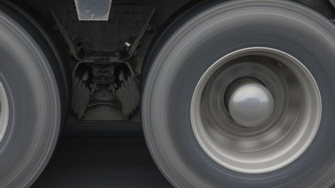 Closeup of truck wheels and tires with suspension. Passing truck on highway.