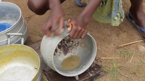 Ghana - 2018: A woman washes the dishes  in a village.