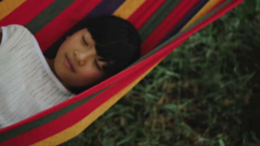 Little girl resting lying on hammock outdoors in slow motion