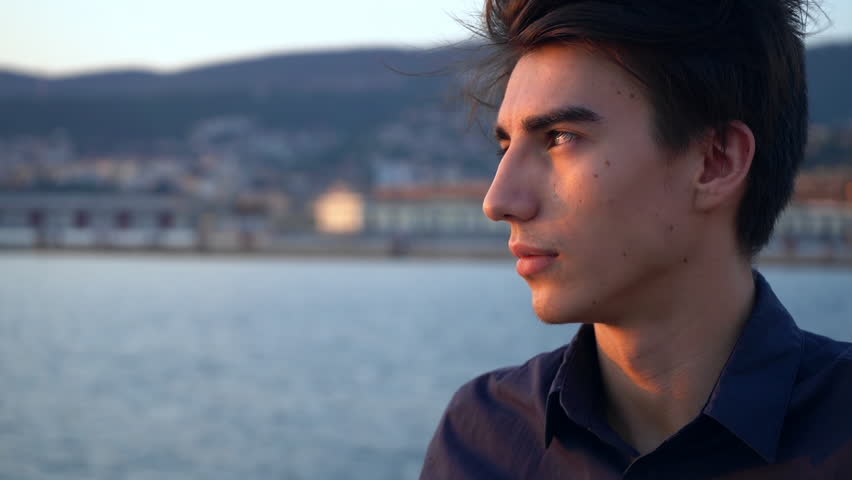 Young man portrait in the city at sunset by the sea