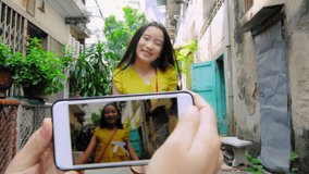 Asian father taking portrait photo or video with smartphone of his asian daughter Bangkok Thailand Asia. Slow motion pov. 
