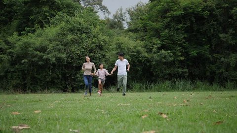 Slow motion of parents with daughter running enjoy in the park 