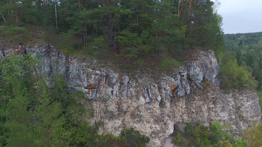 Ranger talking on a walkie-talkie on the edge of a mountain cliff.