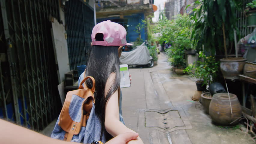 Asian father and daughter walking and holding hands, together looking for an address with a gps navigator on a smartphone in Bangkok city alley way street inThailand Asia. Slow motion hand held pov.  