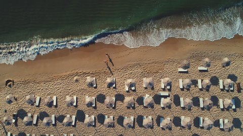 Aerial top view on the beach. Umbrellas, sand and sea waves. Summer holidays. 스톡 비디오