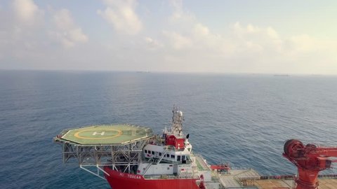 Mediterranean Sea - August 9, 2018: Aerial footage of a Medium size red Offshore supply ship with a Helipad and a large crane