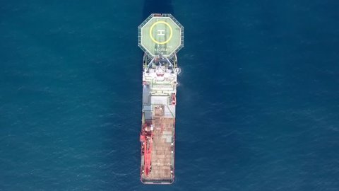 Mediterranean Sea - August 9, 2018: Aerial footage of a Medium size red Offshore supply ship with a Helipad and a large crane
