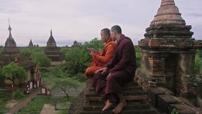 Authentic real monks, using smart phone to view video or photo of sunrise. Over looking view of Bagan Mayanmar / Burma at sunrise. 
