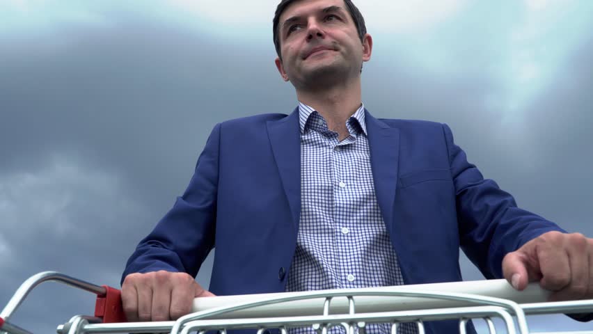 Handsome man carries a cart on parking near the supermarket