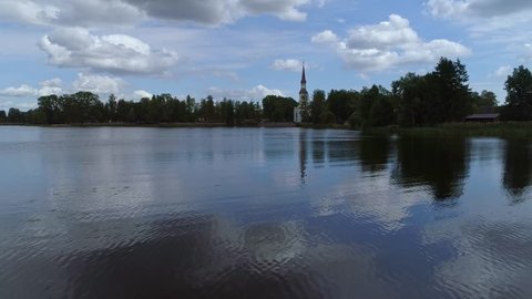 Approaching a protestant church with the mirroring of the lake. Small village church in a green forest.