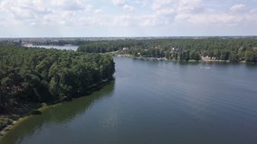 Aerial footage of lake in summer. People sailing and resting in the water seen from above.