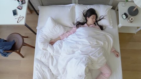 Asian exhausted woman lying in the bed and sleep deeply. She sleeps in different positions and postures.