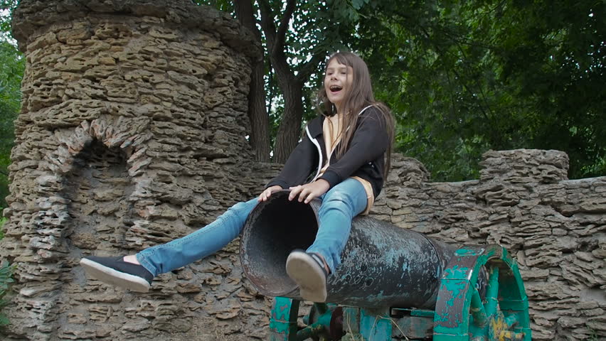 A child is playing with a cannon. A little girl is sitting on a cannon.