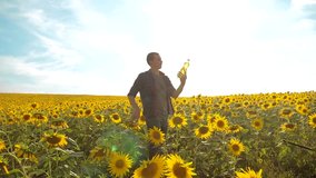 man farmer exploring the field with sunflowers. slow motion video. Man lifestyle farmer hand hold bottle of sunflower oil the field at sunset. man farmer agriculture plastic bottle oil sunflower