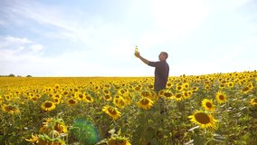 Man farmer hand hold bottle of sunflower oil the field at sunset. man shows on the production of sunflower oil in a field at lifestyle sunset plastic bottle. slow motion video. man farmer agriculture