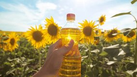 slow motion lifestyle video. Man farmer hand hold bottle of sunflower oil the field at sunset. man farmer agriculture plastic bottle oil sunflower concept. man shows on the production of sunflower oil