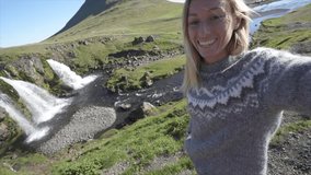 Selfie portrait of tourist female in Iceland at Kirkjufell mountain and waterfall . Women travel discovery fun technology youth culture concept. Tourist female visiting Iceland 