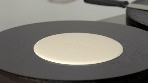 Cook prepares pancakes on the professional surface of the plate in slow motion