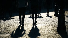 Pedestrians silhouettes at sunset on a cobblestone street