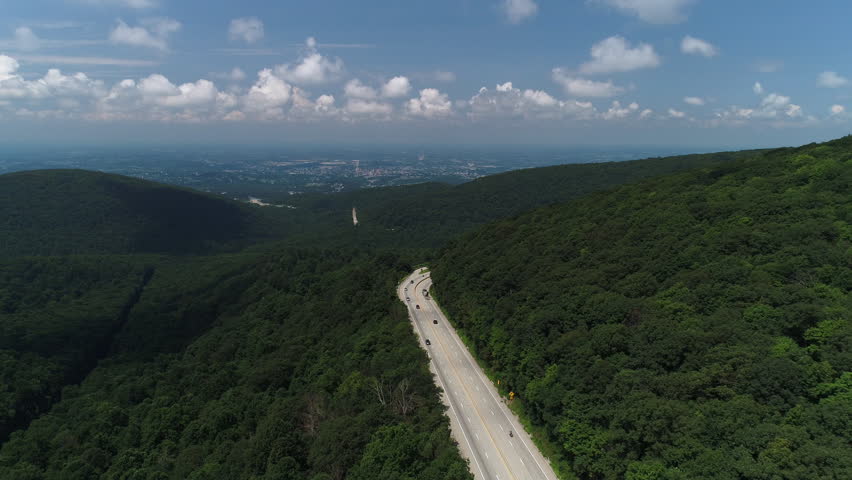 A high angle aerial summer daytime view of the Pennsylvania landscape. The town of Unionville in the distant valley. Traffic on PA RT-40 National Pike in the foreground.  	